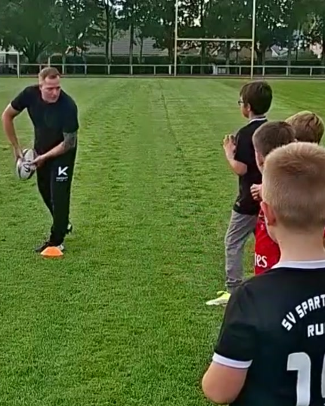 Jörn zeigt beim Kindertraining eine Übung mit dem Rugbyball
