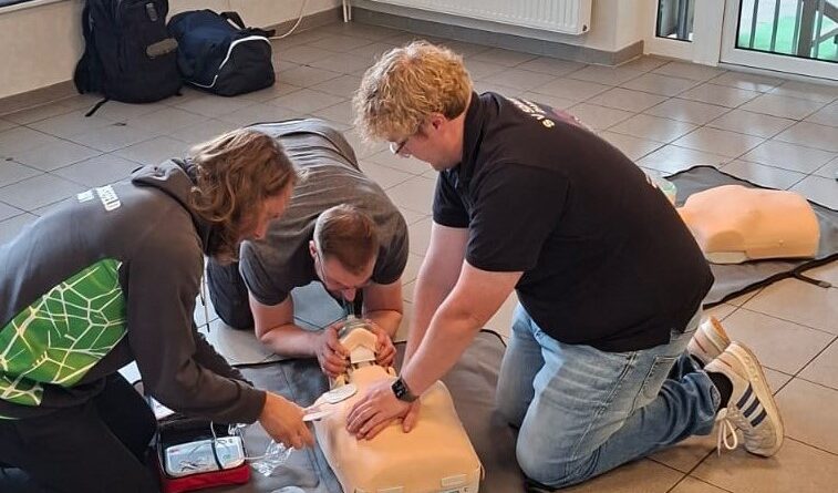 Teilnehmende üben Erste Hilfe an einer Reanimationspuppe beim Rugby-Kurs in Karlshöfen